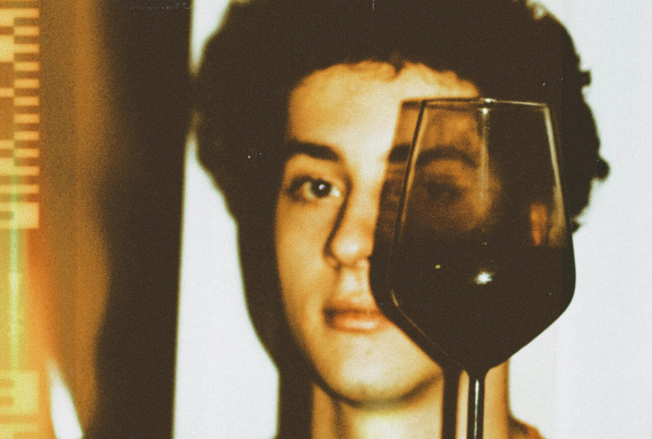 A vintage artistic photo of a face seen behind a wine glass